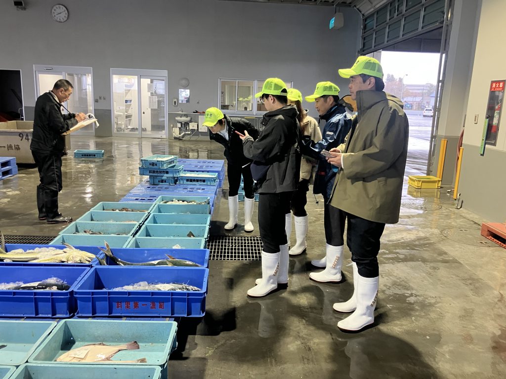 収穫した鮭の説明を受ける社員達