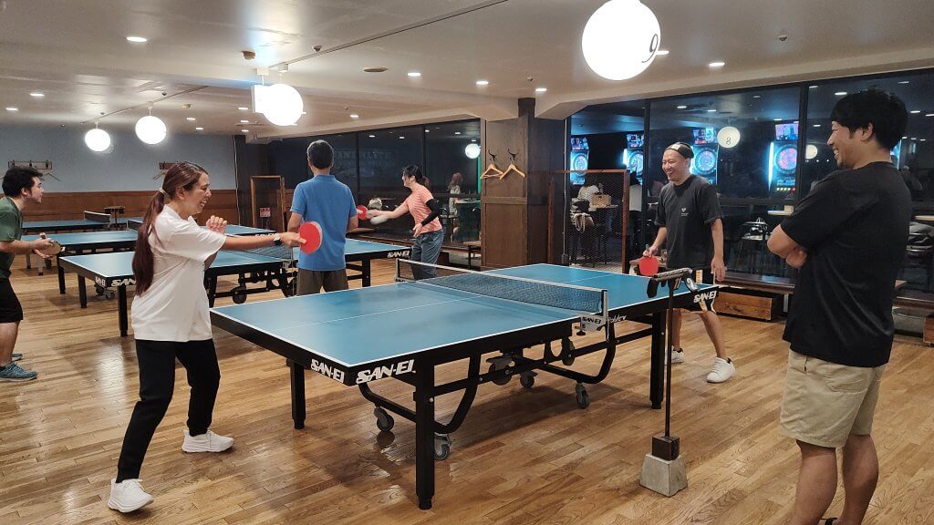 卓球台の両側に分かれ笑顔で卓球を楽しんでいる部員達の様子